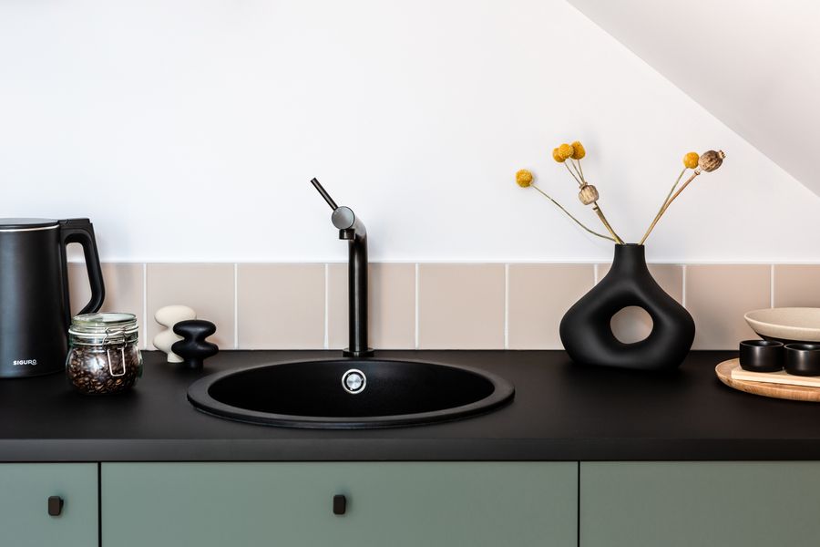 Finished kitchen counter with a dark sink and mixer tap